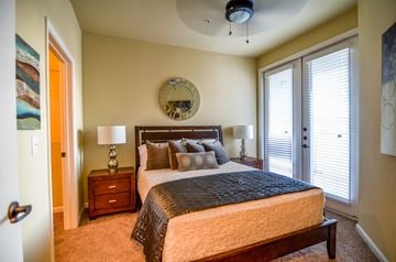 Odessa apartment for rent - A bedroom with a bed, nightstand, and a round mirror on the wall.