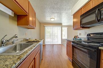 Midland apartment for rent - A kitchen with wooden cabinets and a black stove top oven.