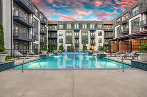 Farmers Branch apartment for rent - A beautiful pool courtyard here at Crosby at the Brickyard with a sparkling pool, modern buildings, private balconies, lounge seating, and a colorful sunset sky, creating a relaxing, upscale outdoor retreat.