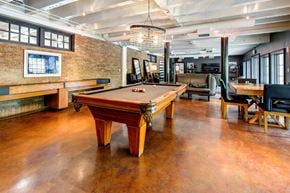 Fort Worth apartment for rent - A pool table is in the middle of a room with a brick wall.