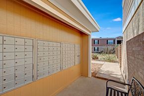 Odessa apartment for rent - A covered community mailbox area here at Golden Crest with neatly organized mailboxes, neutral-toned siding, and a shaded walkway that leads into the landscaped courtyard, offering a convenient and accessible mail pickup space.
