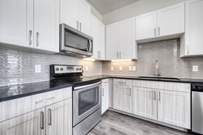 Rowlett apartment for rent - A kitchen with white cabinets and a black counter top.