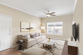Mansfield apartment for rent - A living room here at Landing at Mansfield with a beige sofa, neutral wall art, light rug, wood coffee table, ceiling fan, and a bright window bringing in natural light.