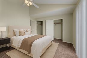 Midland apartment for rent - A spacious bedroom here at Las Colinas with soft beige carpet, neutral walls, and a vaulted ceiling with a ceiling fan. Large closets with sliding doors and a bright window with vertical blinds create an airy, comfortable, and inviting space.