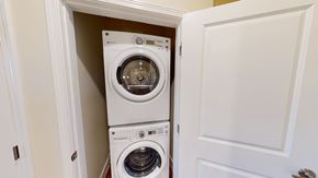 Odessa apartment for rent - A convenient laundry closet here at Latitude 31 Apartments featuring a stacked front-loading washer and dryer neatly tucked behind a white paneled door. Neutral walls, clean trim, and a compact layout provide an efficient in-home laundry solution that maximizes space while keeping appliances discreet and easily accessible.