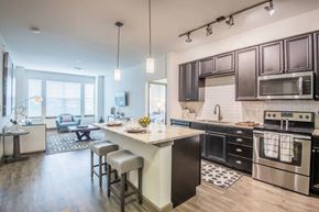 Mckinney apartment for rent - A modern kitchen with dark brown cabinets and a white island.