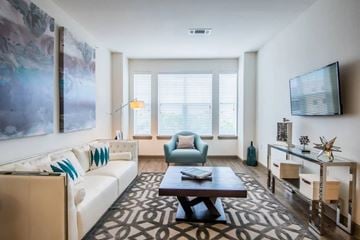 Mckinney apartment for rent - A living room with a white couch, a blue chair, and a painting on the wall.