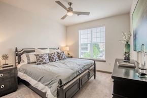 Mckinney apartment for rent - A bedroom with a large bed and a ceiling fan.