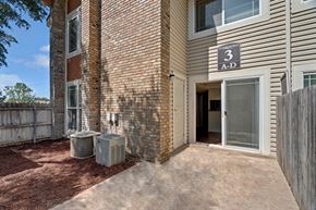 Odessa apartment for rent - A private ground-level patio here at Summertree Place featuring a concrete patio surface, a sliding glass door leading into the apartment, brick and siding exterior walls, landscaped mulch along the building, and a fenced boundary that creates a defined outdoor space with convenient access to the interior.