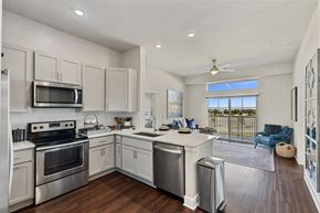Frisco apartment for rent - A modern kitchen here at Waterford Market with a large island and stainless steel appliances, overlooking the living room. A sliding door sits at the far back wall, creating a bright and open living space.