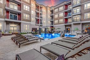 Frisco apartment for rent - A resort-style pool courtyard here at Waterford Market with a central swimming pool, in-water loungers, surrounding sun chairs, landscaped seating areas, and modern apartment buildings enclosing the space.