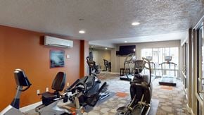 Salt Lake City apartment for rent - A gym with orange walls and a variety of exercise equipment.