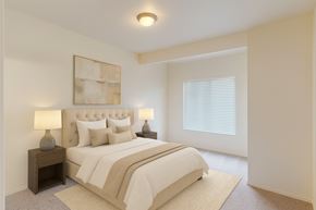 Salt Lake City apartment for rent - A bedroom space here at Citifront with a beige upholstered bed, neutral bedding and pillows, matching nightstands with gray lamps, soft carpet, light walls, and a bright window with white blinds.