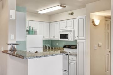 Sandy apartment for rent - A kitchen with white cabinets and a granite counter.