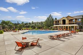 Sandy apartment for rent - A large outdoor pool area with a table and chairs.