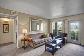 Sandy apartment for rent - A living room with a couch, a coffee table, and a mirror.