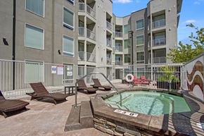 Salt Lake City apartment for rent - A pool surrounded by chairs and a fence in front of apartment buildings.