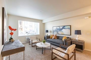 Wenatchee apartment for rent - A living room with a grey couch, a coffee table, and a painting on the wall.