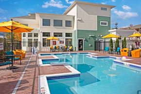 Wenatchee apartment for rent - A resort-style pool area here at 600 Riverside with clear blue water, bright yellow umbrellas, colorful lounge seating, and a sunny, welcoming deck for relaxing and socializing.