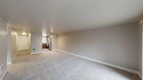 Lynnwood apartment for rent - A living and dining area here at A'Cappella with soft gray walls, wide open carpeted floor, bright entry hall, and open view toward the kitchen, creating a spacious, clean, and welcoming empty layout.