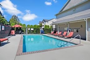 Covington apartment for rent - A swimming pool with red lounge chairs and a metal fence.