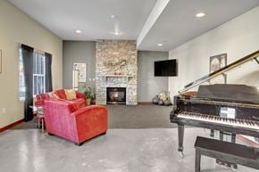 Covington apartment for rent - A living room with a red couch, a piano, and a stone fireplace.