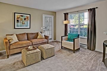 Everett apartment for rent - A living room with a brown couch, a green chair, and a painting on the wall.