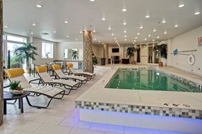 Renton apartment for rent - A large indoor swimming pool with lounge chairs and a tiled edge.