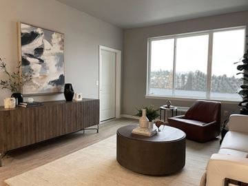 Wenatchee apartment for rent - A living room with a brown couch, a brown coffee table, and a large painting on the wall.