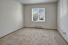 Everett apartment for rent - A room with a carpeted floor and a window showing a view of a house and trees.