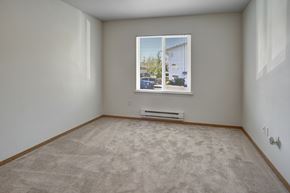 Everett apartment for rent - A quiet bedroom here at Lake Park featuring soft carpeted flooring, light neutral walls, and a centered window with horizontal blinds that bring in natural daylight, with baseboard heating below the window and a simple rectangular layout that offers flexibility for a bed, dresser, and additional furniture.