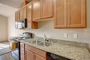 Wenatchee apartment for rent - A bright kitchen here at Riverside 9 featuring warm wood cabinetry, granite countertops, stainless steel appliances, a double sink, and ample counter space for cooking and entertaining.