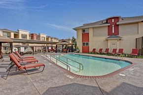 Wenatchee apartment for rent - A pool surrounded by red chairs and a building in the background.