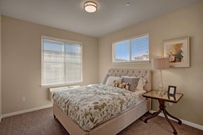 Moses Lake apartment for rent - A bright bedroom here at Solara with a soft upholstered bed, large windows with blinds, plush carpet, and a stylish bedside table with lamp creating a comfortable, relaxing retreat.