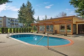 Federal Way apartment for rent - A charming outdoor pool here at Soundview with clear blue water, surrounding patio space, and a nearby clubhouse creating a relaxing and inviting setting.