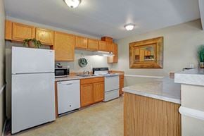 Federal Way apartment for rent - A functional kitchen here at Soundview with warm wood cabinets, white appliances, spacious countertops, and breakfast bar creating a practical and inviting cooking space.