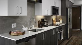 Kirkland apartment for rent - A kitchen here at Uptown at Kirkland Urban featuring sleek white countertops, modern stainless steel appliances, and stylish two-tone cabinetry, creating a bright, polished, and highly functional cooking space.