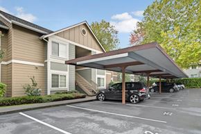 Kenmore apartment for rent - A covered parking area here at Vermont featuring convenient reserved spaces, protective overhead shelter, and attractive building exteriors, creating a clean, secure, and welcoming arrival space for residents.