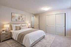 Kenmore apartment for rent - A bedroom here at Vermont featuring soft carpet, large closet doors, neutral bedding, bedside tables with lamps, and abstract wall art, creating a cozy, calm, and inviting retreat.