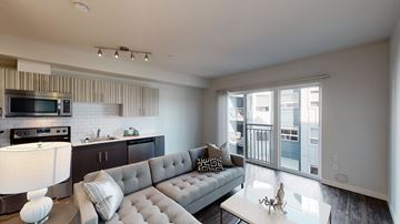 Seattle apartment for rent - A modern living room with a grey sofa and a kitchen area with a stove and oven.