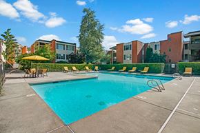 Lake Forest Park apartment for rent - A refreshing outdoor swimming pool here at Watercrest with clear blue water, surrounding lounge chairs, and shaded seating areas, creating a relaxing and enjoyable community space under a bright open sky.