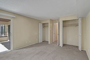 Lake Forest Park apartment for rent - A spacious, empty bedroom here at Watercrest with soft carpet, neutral walls, and dual closets, featuring a sliding glass door leading to a private balcony, creating a bright and comfortable living space.