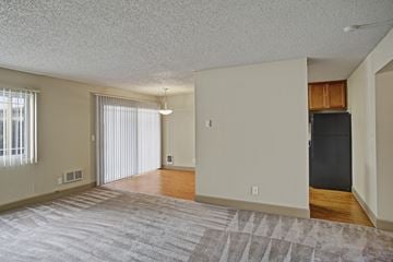 Lynnwood apartment for rent - A spacious living room with a grey carpet and a black refrigerator in the corner.