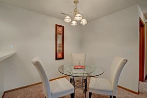 Milwaukee apartment for rent - A glass table with a red book on it and two chairs.