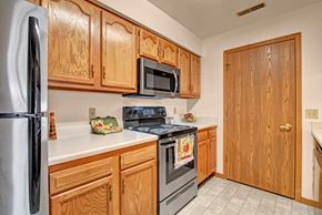 Milwaukee apartment for rent - A bright kitchen here at Arbor Ridge featuring warm wood cabinets, white countertops, and stainless steel appliances. The functional layout and clean finishes create a welcoming, practical space for everyday cooking.