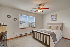 Milwaukee apartment for rent - A bright bedroom here at Arbor Ridge featuring white bedding with beige accents, a dark wood bed frame, and a matching dresser. Large window and soft carpet create a calm, inviting retreat.