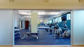 Milwaukee apartment for rent - A modern fitness center here at Avenir featuring cardio machines, free weights, and open workout space. The bright windows and clean layout create an energizing, spacious, and motivating environment.