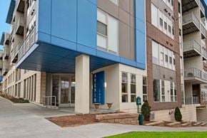 Milwaukee apartment for rent - A welcoming exterior entrance here at Avenir featuring modern blue architectural accents, clean lines, and large windows. The contemporary design and landscaped surroundings create a polished, inviting first impression.