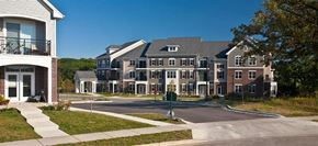 Madison apartment for rent - A large, multi-story residential building with a brick facade and a driveway in front.