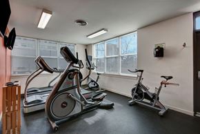 Milwaukee apartment for rent - A bright fitness center here at Latitude featuring large corner windows, modern cardio equipment, and a clean, open layout, creating an energizing and welcoming workout space.